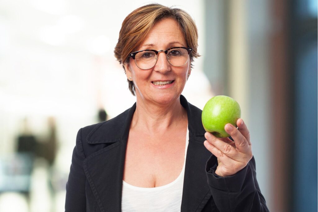 Mujer en oficina disfruta de una manzana