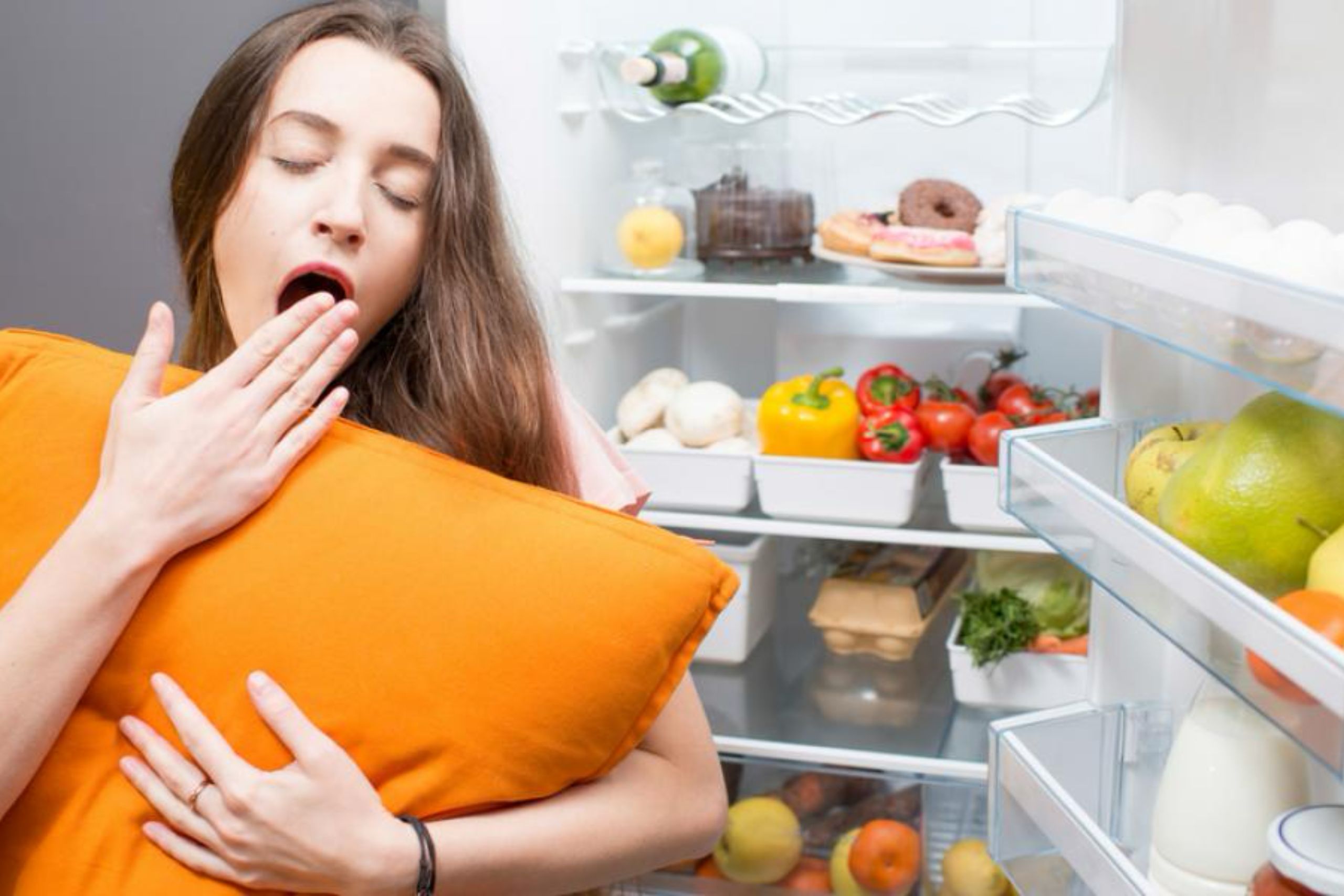 Foto de persona bostezando frente al refrigerador