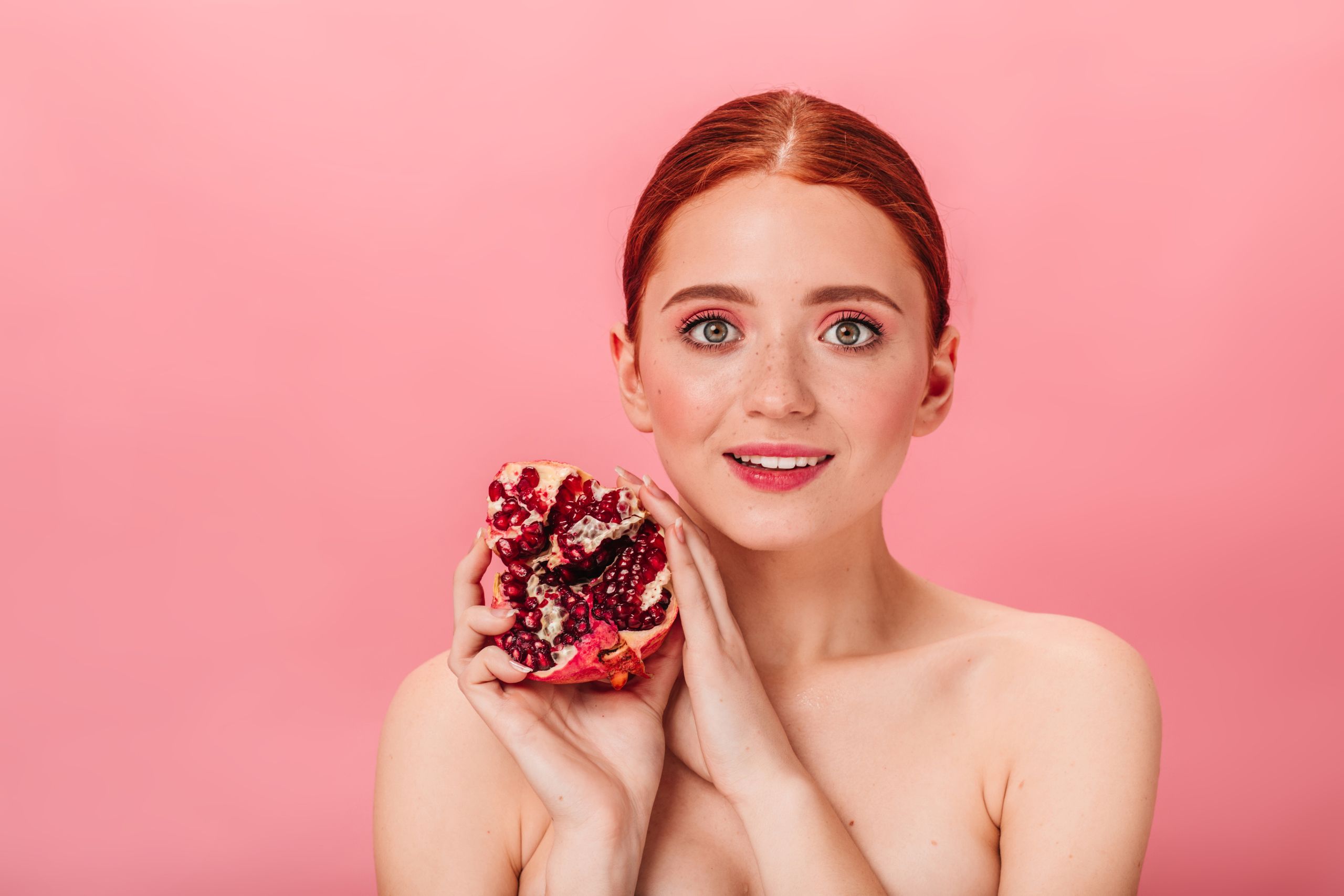 Mujer joven con piel radiante sosteniendo una granada