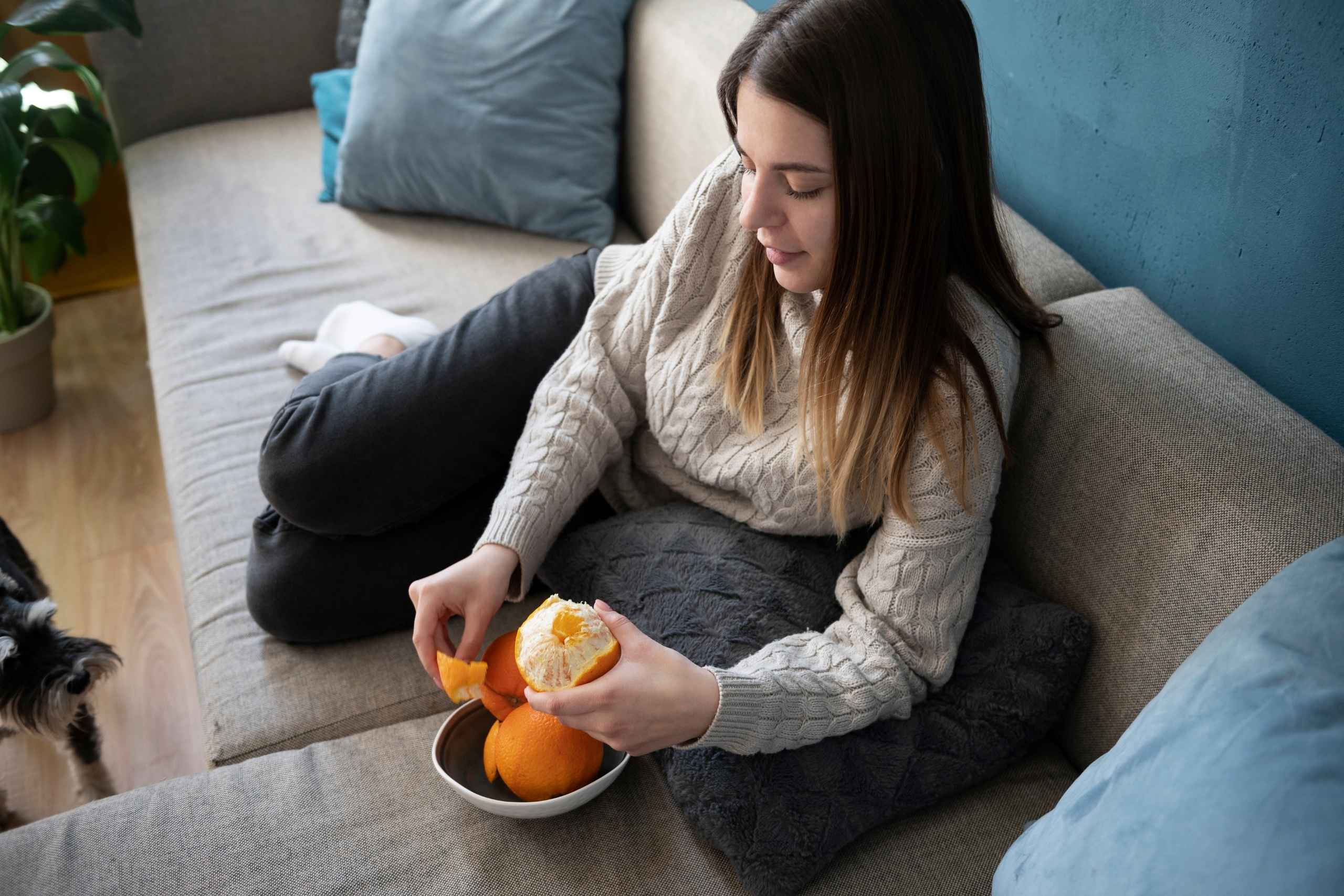 Mujer joven en clima frío disfruta una naranja fresca como snack